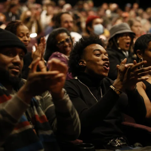 Image of people smiling and clapping in a movie theater.