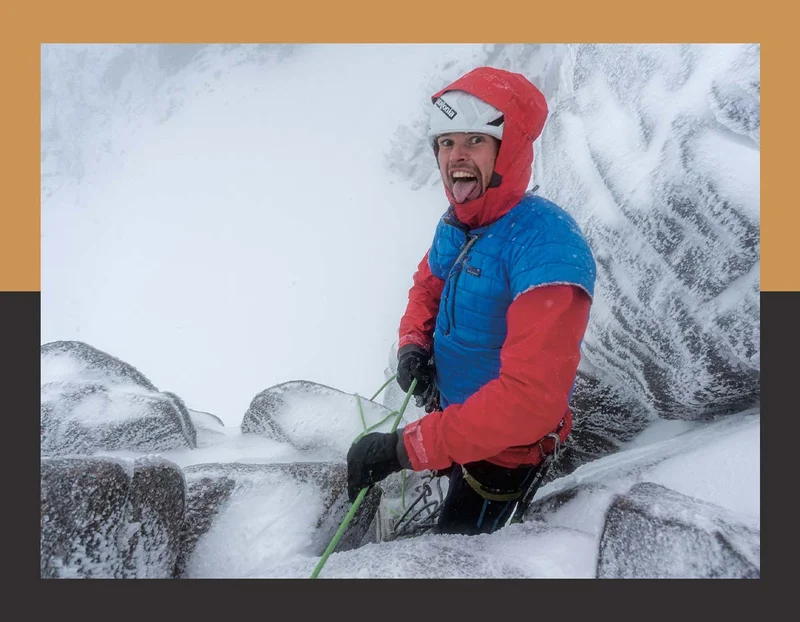 Alt: A person stands on a snowy mountain, holding a rope, and sticking their tongue out.