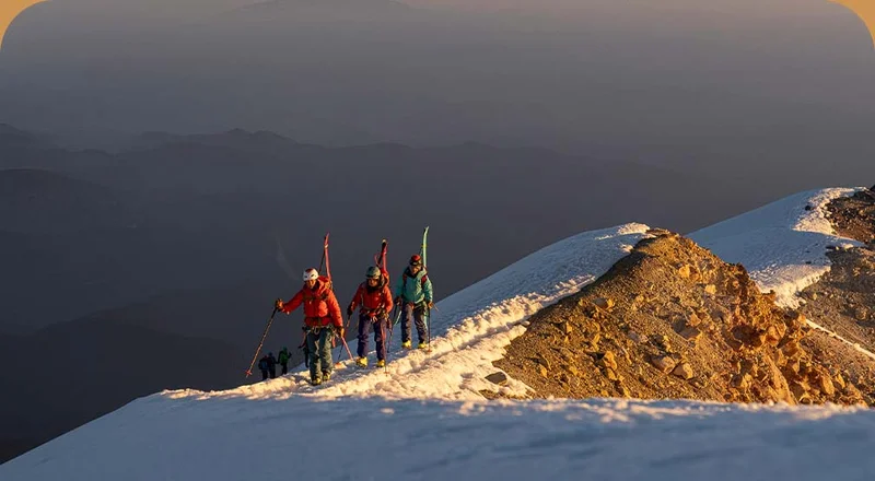 A group of people walking up a mountain with skis on their backs.