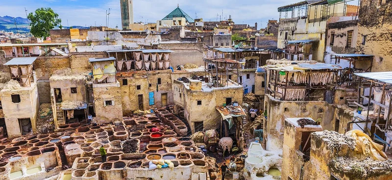A view of Chouwara Tannery in Fes el Bali (Old Fes), Medina, showcasing traditional leather tanning processes with colorful dye pits and bustling activity.
