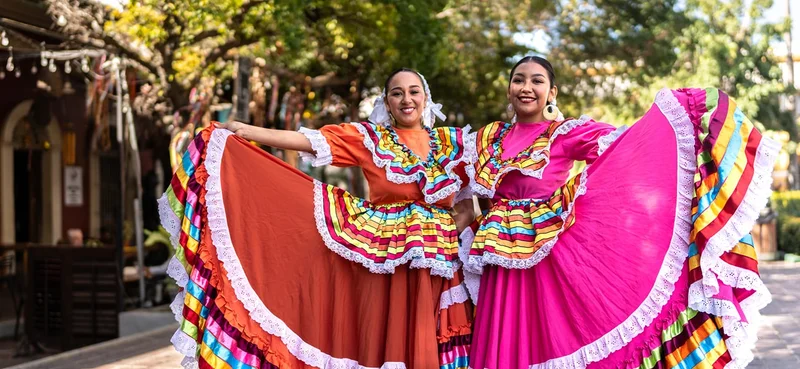 Portrait of women dancers wearing traditional Mexican clothing, posing outdoors.