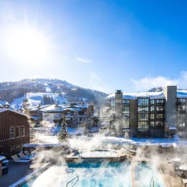 A steamy pool at Chateux Deer Valley, snowy mountains in the background.