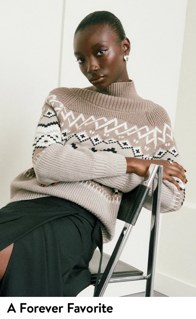 A woman wearing a Fair Isle turtleneck sweater with a black skirt.