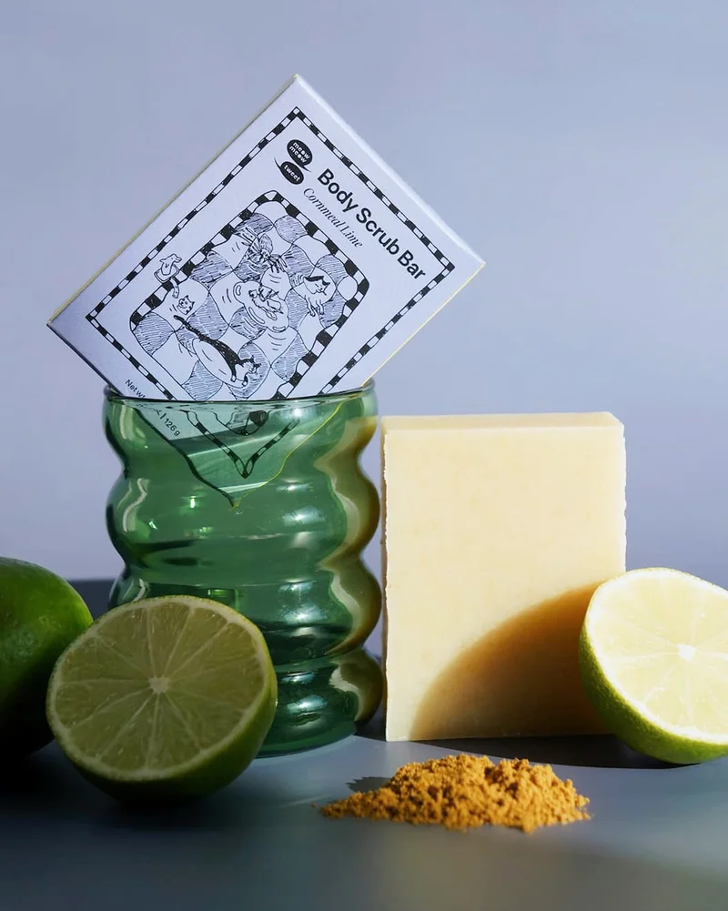 A light blue box propped in a bumpy green glass with limes and a small pile of cornmeal