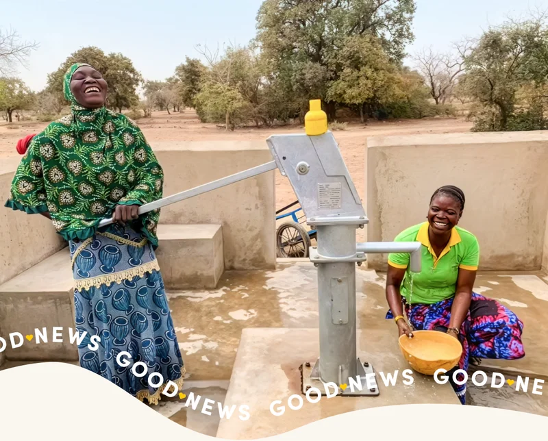 Two women fill up water from a handpump.