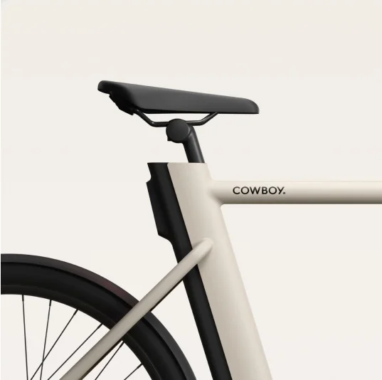 A render. a Cowboy e-bike frame, showing a minimalist design with a black saddle and sand-coloured frame.