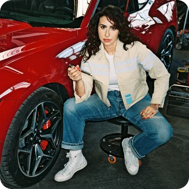 A woman checking the tire pressure on a red 2024 Ford Mustang® coupe