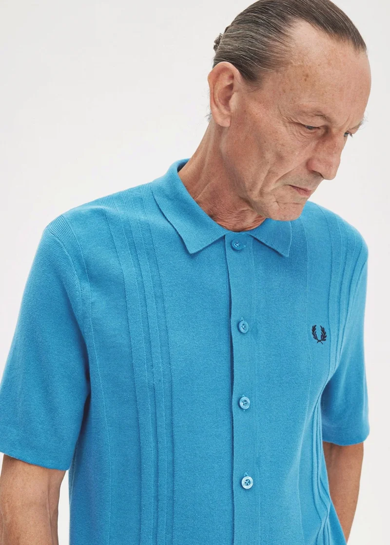 Image of older male modelw wearing a bright blue knitted button up short sleeved shirt