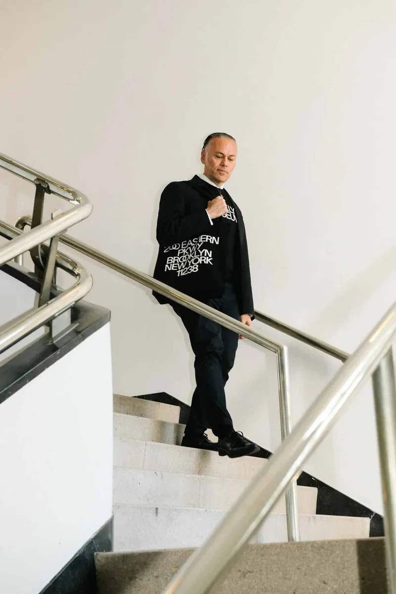 A man descending a staircase wearing a Brooklyn Museum sweatshirt and tote