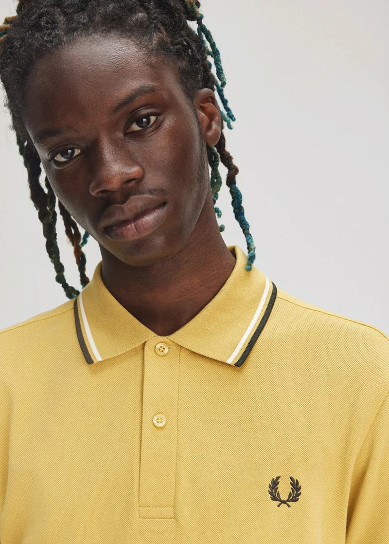 Black male model wears a Honeycomb M3600 Fred Perry Shirt with Snow White and Court Green tipping