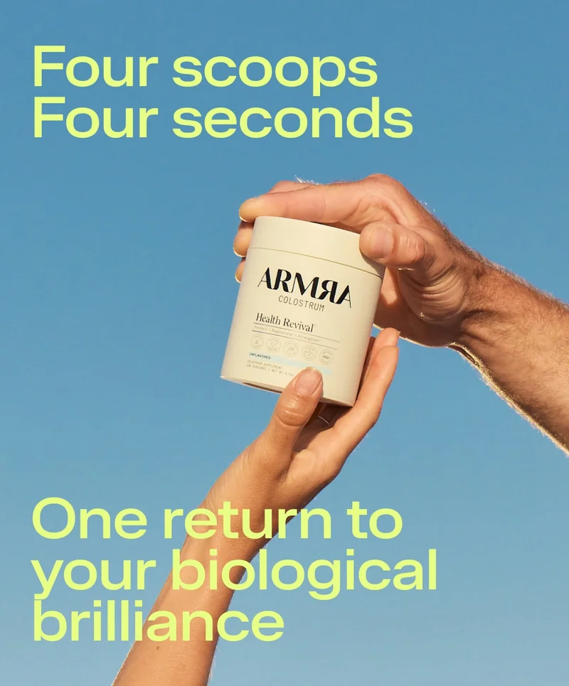 Hands holding a jar of ARMRA Colostrum against a blue sky, highlighting the simplicity of the daily routine.