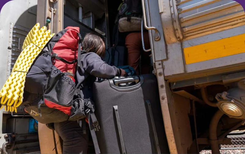 A person steps onto a train carrying their climbing gear.