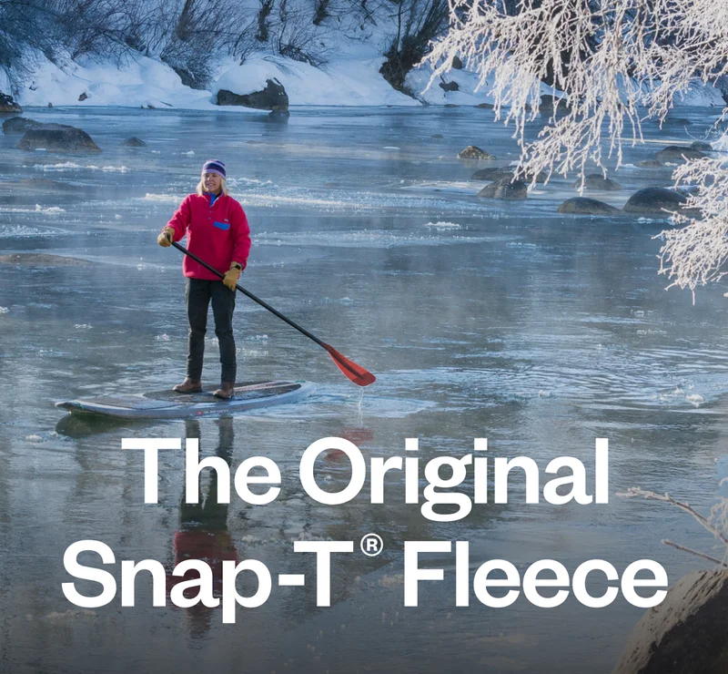 A person paddle boarding on a partially frozen river.