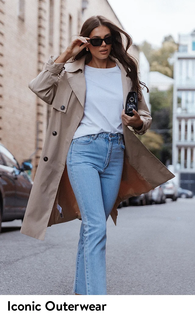 A woman wearing a trench coat with a white top and blue jeans.