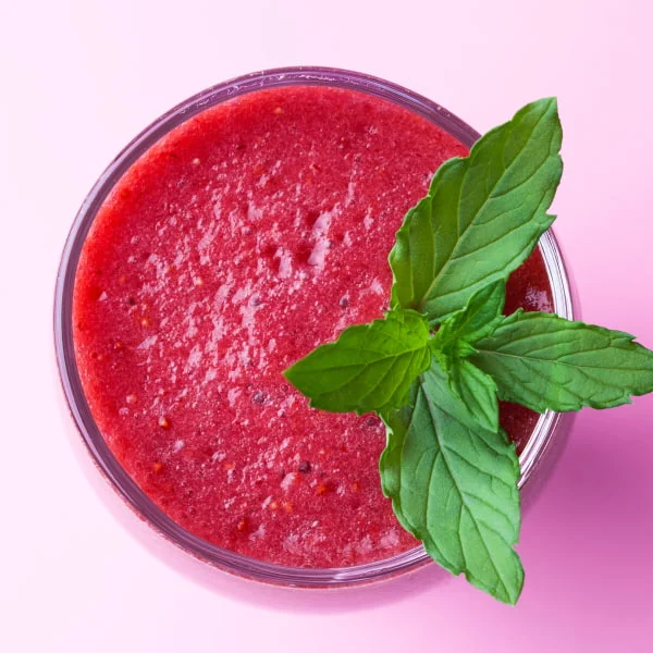 Image of a blackberry frozen drink with a mint leaf on top.