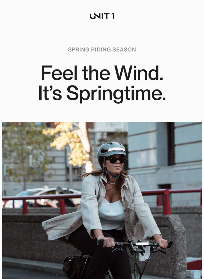 Woman riding a bike wearing a UNIT 1 helmet on a sunny spring day.