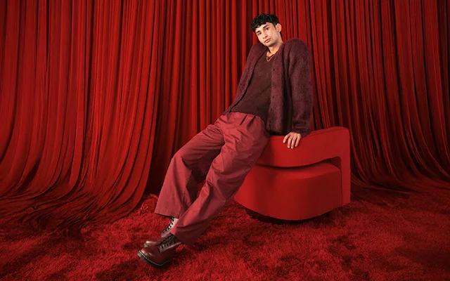 A person wearing all red posting in a red room.