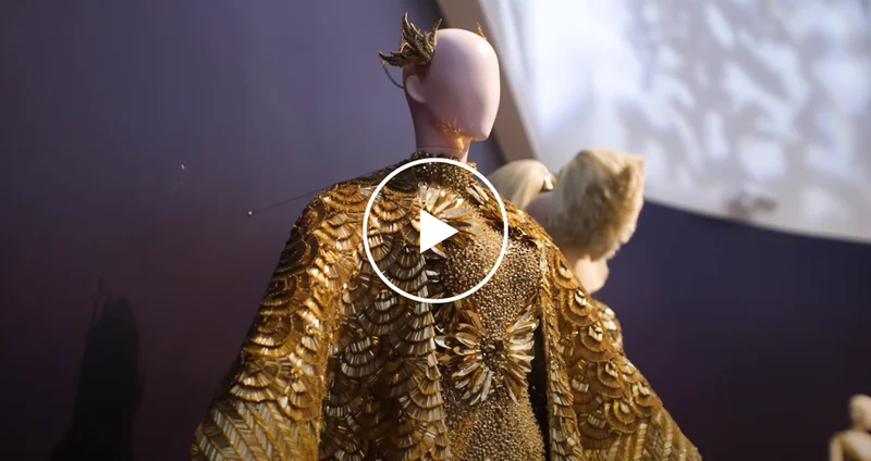 A mannequin wears a gold cape and dress