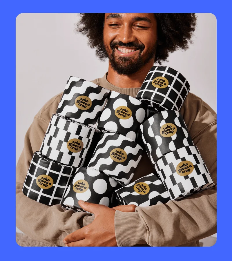 Image: Man holding tons of Who Gives A Crap toilet paper