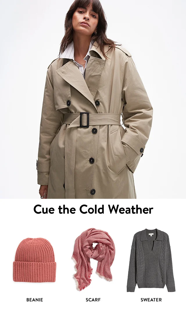 A woman wearing a trench coat.  A grey sweater, pink beanie and red scarf.