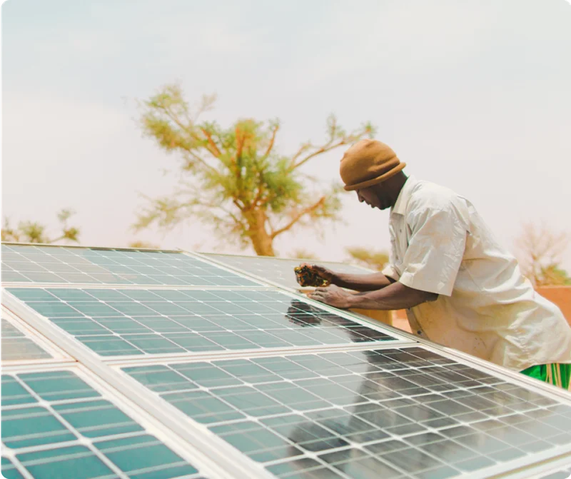 A Malian man cleans the solar panels that power his community's sustainable tap stands