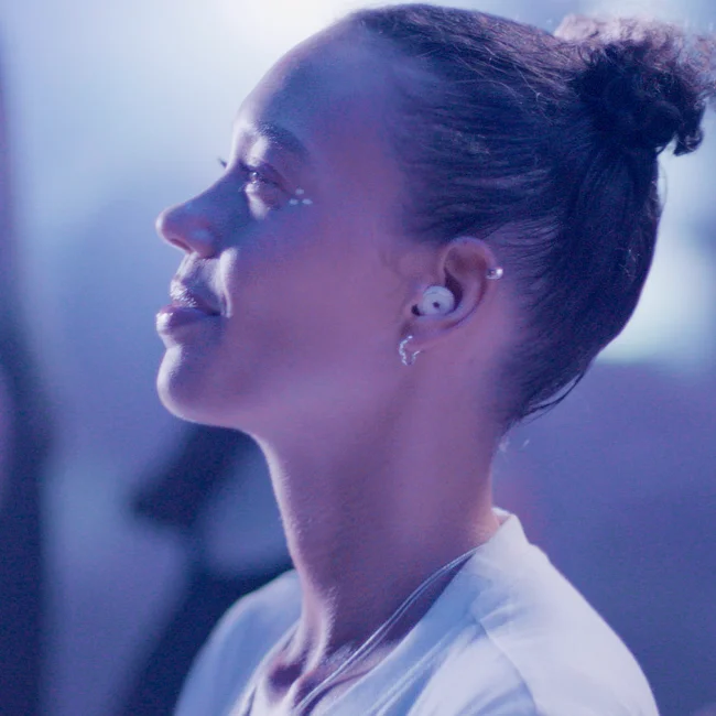 A woman in profile smiles at a concert while wearing Loop Switch.