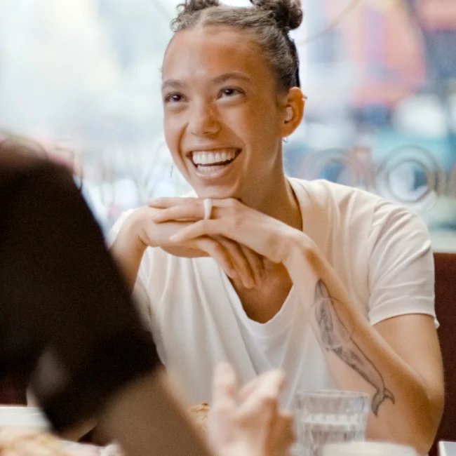 A woman wearing Loop Switch earplugs laughs at a cafe.