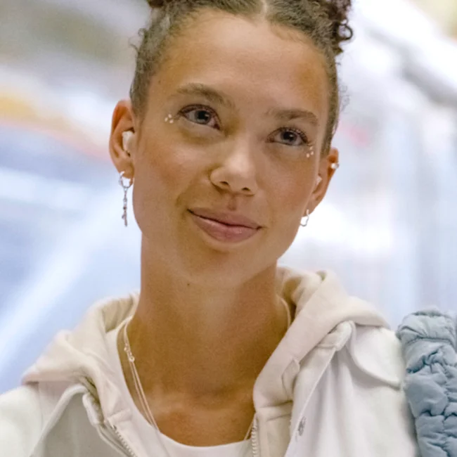 A smiling woman wearing Loop Switch earplugs looks just off camera.