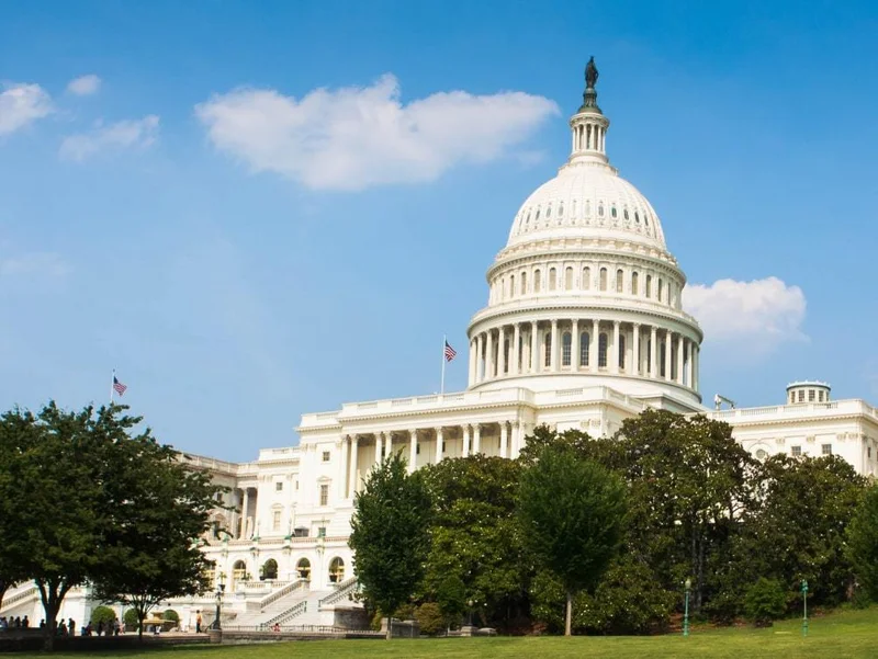 Image description: The United States Capitol building set against a blue sky with sparse clouds.