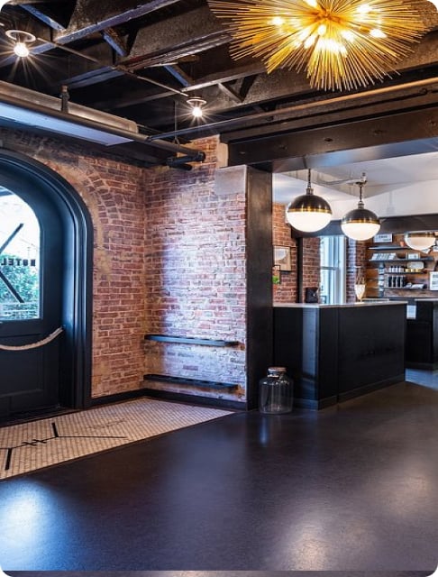 Image description: Hotel lobby with dark accents and a brick wall with gold and brass lighting accents.