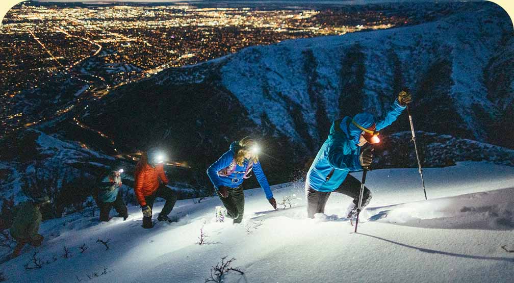Four people hiking up a snowy mountain in the dark.