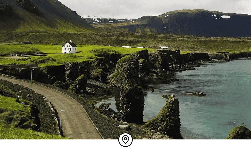 Image Description: A seaside road in Iceland set against green rolling hills