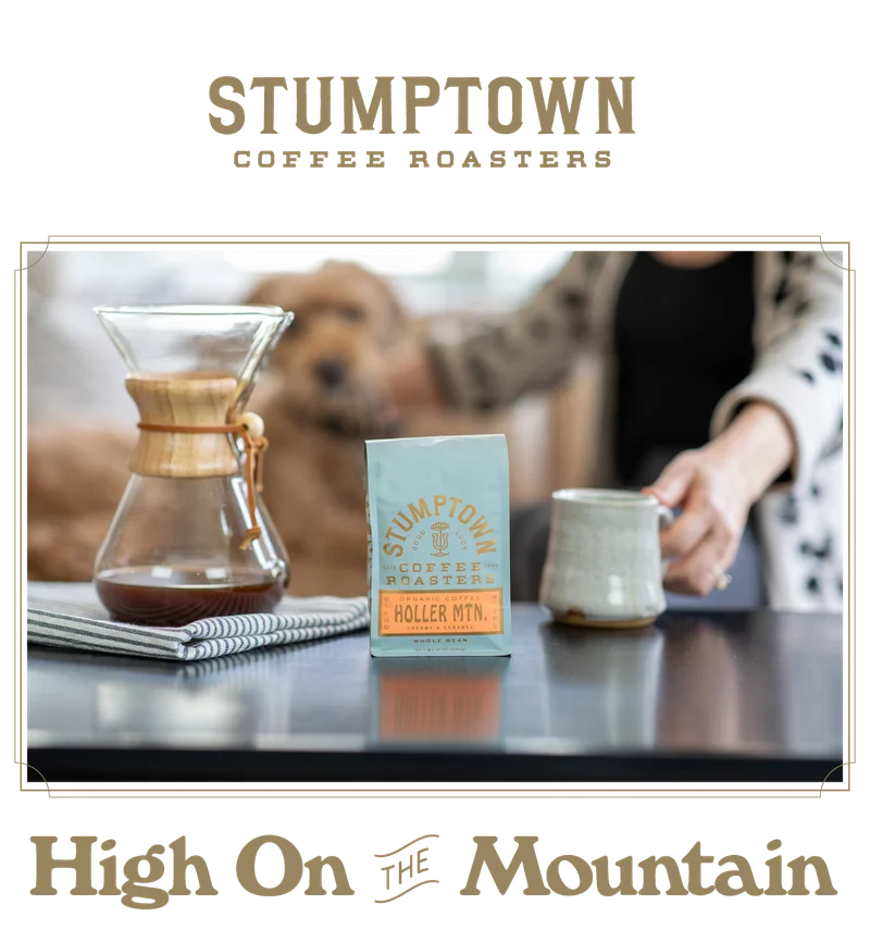 Stumptown Coffee “Holler Mountain” bag on a kitchen counter beside a Chemex and ceramic mug, with a person reaching for the mug and a dog softly blurred in the background. Text below reads “High On the Mountain.”