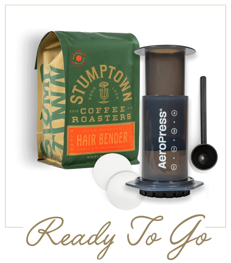 AeroPress and bag of Stumptown Hair Bender coffee with scoop and filters. Text reads “Ready To Go.”