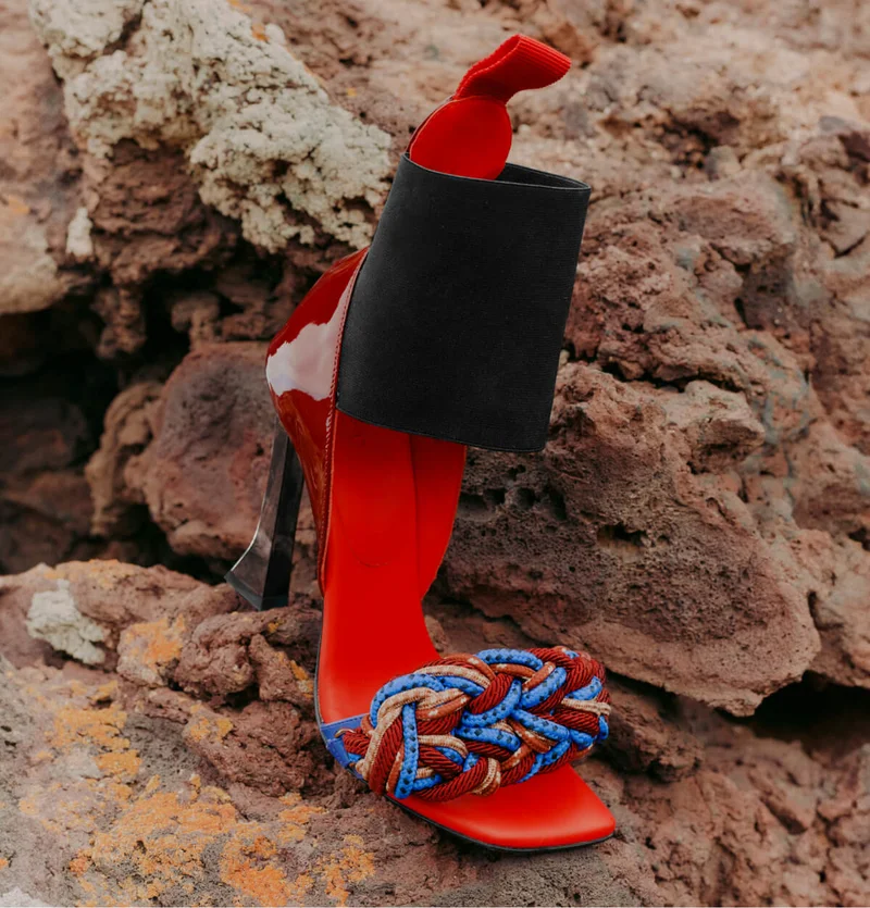 Patent-leather sandal with elastic band, woven detail and flared heel.