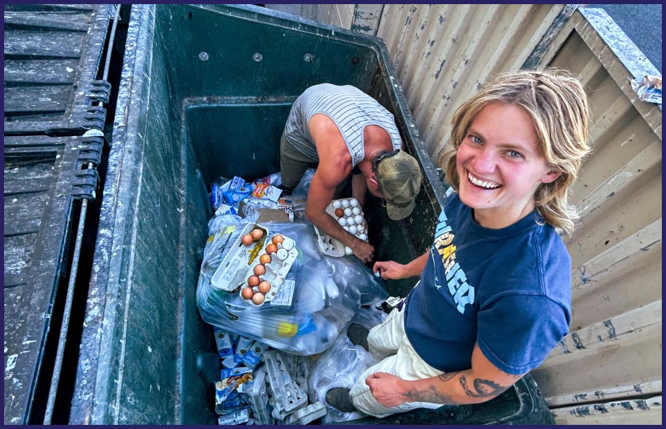Two people dumpster diving for food.