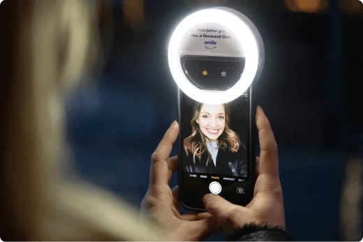 Person using the SDC Selfie light attached to their mobile phone.