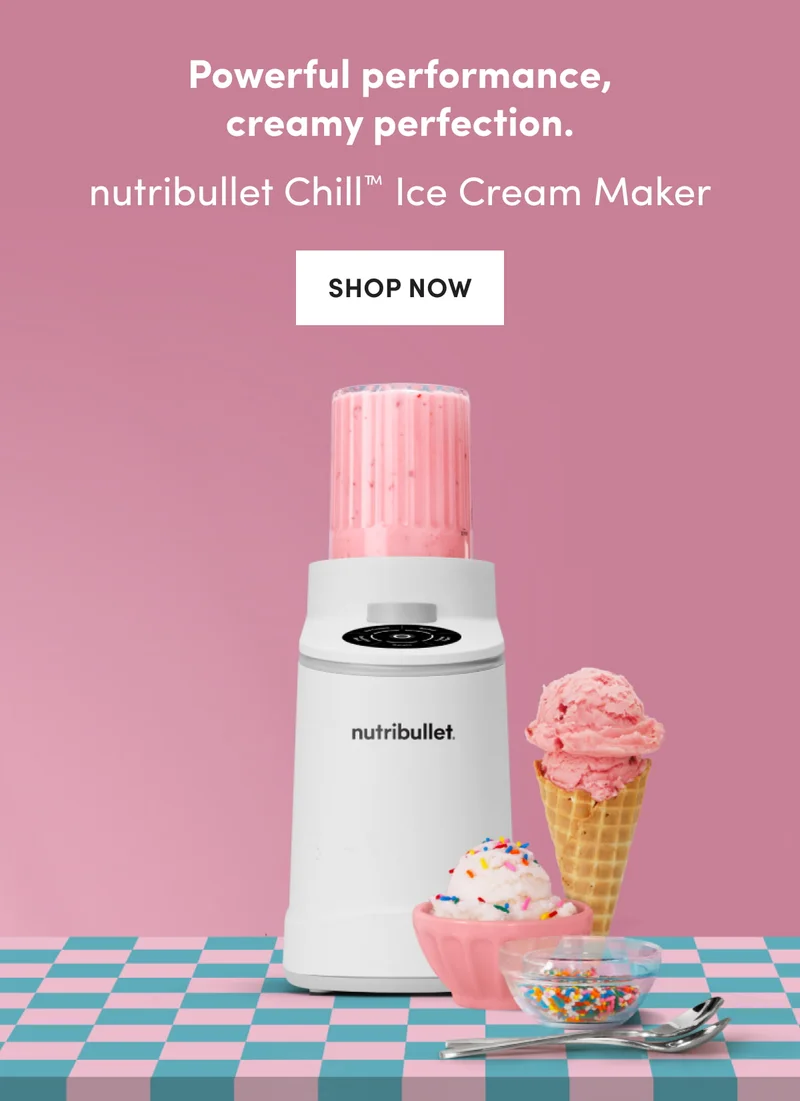 A white nutribullet Chill blender with a pink frozen mixture stands on a teal and pink checkered surface next to a pink sorbet scoop in a waffle cone and a small bowl of ice cream with sprinkles.