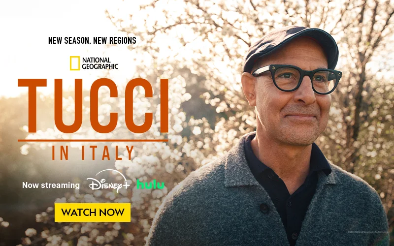 A man in a hat and glasses stands in front of a tree, promoting a new season of a show.