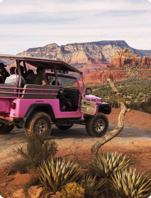 Image Description: Travelers in a pink Jeep admiring Sedona’s beautiful red rock buttes in the distance