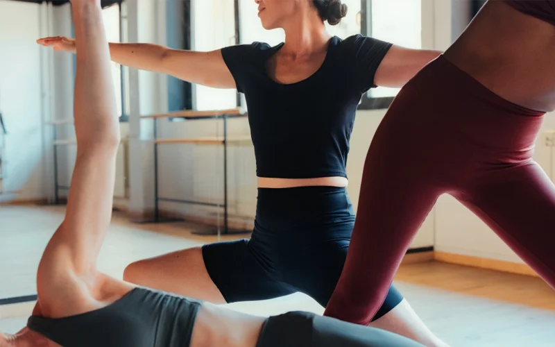 Three people stretch in different yoga poses.