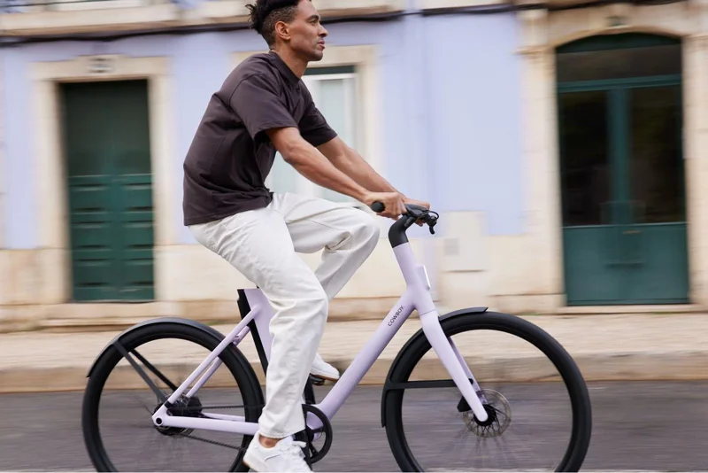 A photograph. A man rides a Cowboy Cruiser ST Lavendar.