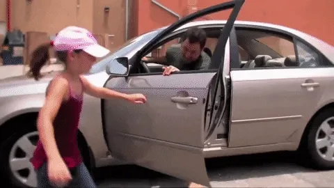 A girl jumping into a car and driving off.