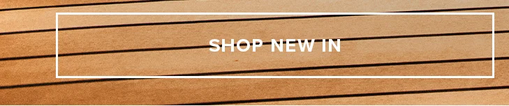 Shop New In button on a wooden background. Discover new arrivals now.