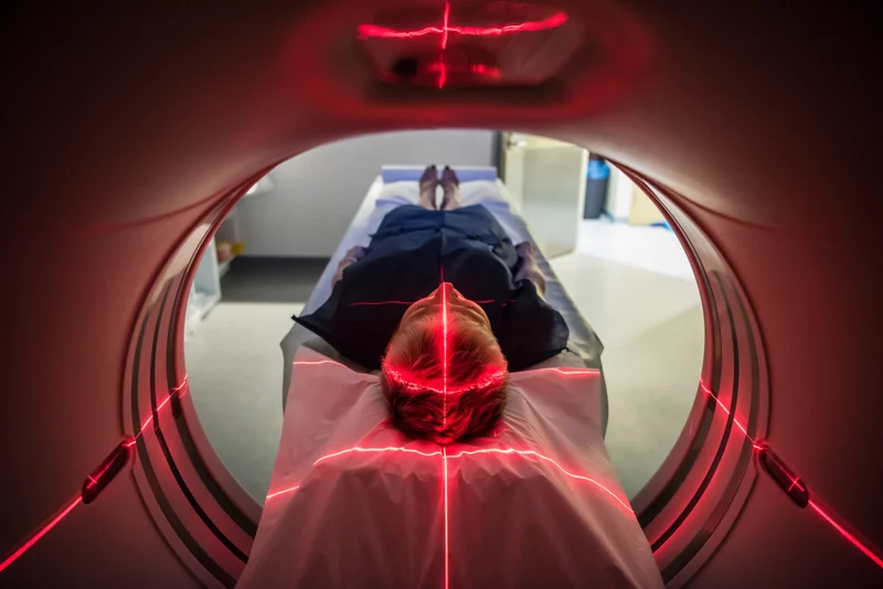 A person in an MRI machine has lasers moving over their body.