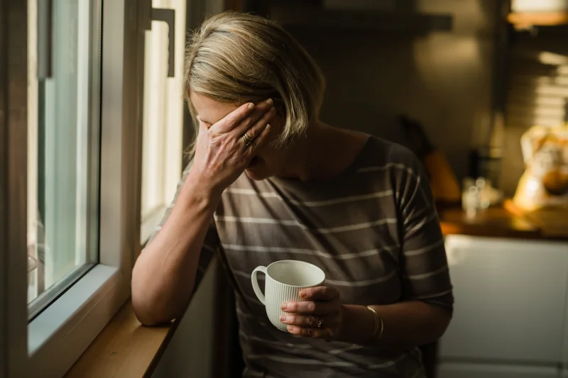 A woman holds her head in her hands.