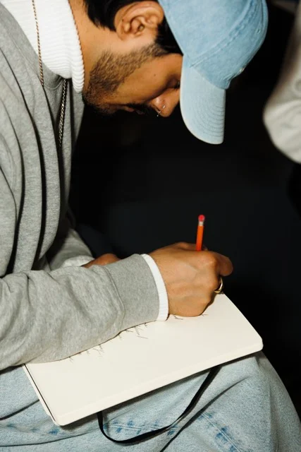 A person writing in a notebook with a pencil