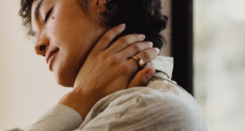 Relaxed person touching neck wearing Oura Ring