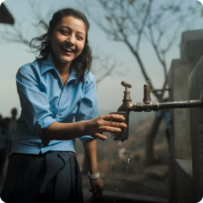 A girl fills her cup with clean water in Nepal