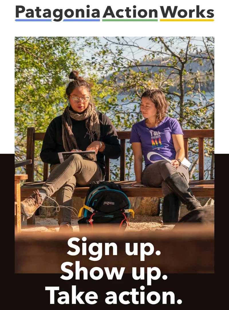 Two people sitting on a bench outside discussing something.